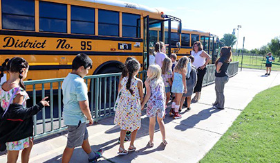 Staff assisting students onto a bus