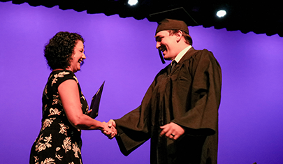 Male graduate in gown receiving GED