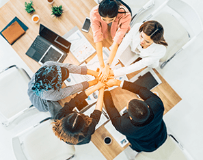 co-workers sitting in a circle with hands in the middle