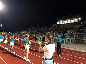 student taking pictures of cheerleaders