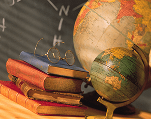 a couple of globes next to a stack of books with a pair of glasses sitting on top