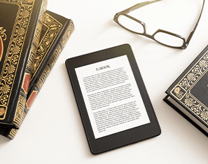 e-reader sitting next to books and a pair of glasses