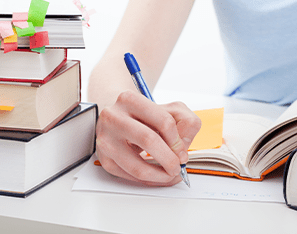 person sitting and writing in a notebook