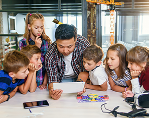 teacher and group of students looking at a tablet device