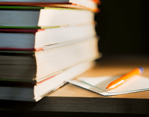 stack of books next to a notebook and pencil