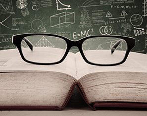 reading glasses sitting on top of a book by a chalkboard