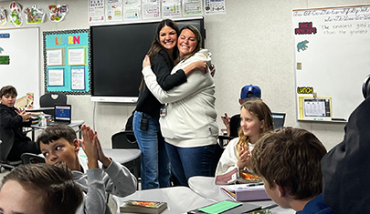 Two adults hugging in classroom