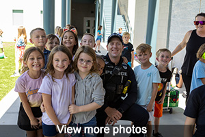 A police officer outside posing with children - view more photos