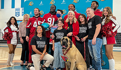 AZ Cardinal players, cheerleaders and dog posing for group picture with Kevin's family and staff member