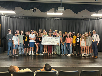 Eastmark Junior High's Allie Sakfi with large check surrounded by students