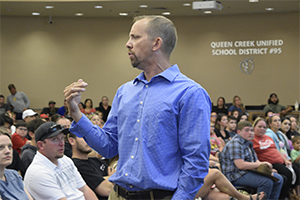 Adult in blue shirt speaking with group of students and parents