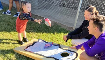 Two high school students working with a preschool student outside