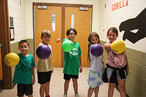 Five students holding dodgeballs for a photo opportunity