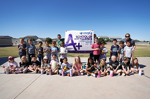 Students outside holding A+ banner