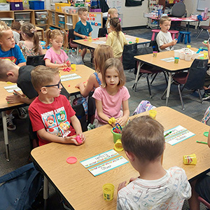 Young children at tables working with Play Doh