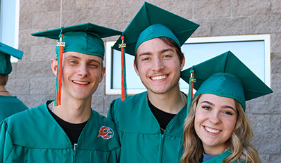 three students in graduation cap and gown