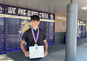 Keegan Roque holds his President's Gold Volunteer Service Award and wears his medal