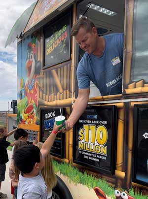 Person in Kona Ice truck handing shaved ice to students