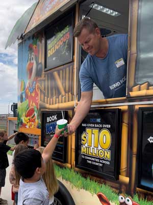 Person in Kona Ice truck handing shaved ice to students