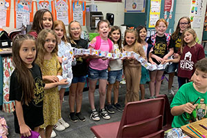 Students holding a Patriot Day paper chain-link in the classroom