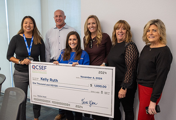 Group photo of Kelly Ruth holding a large $1,000 check surrounded by other staff members