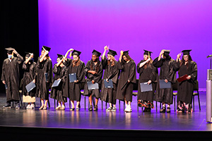 QCUSD Adult Graduates in caps and gowns on stage