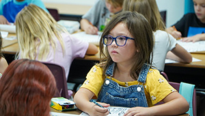 Little girl wearing glasses coloring