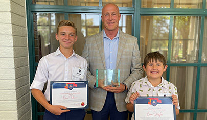 Two students and Superintendent holding their awards