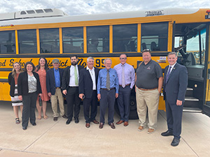 School Facilities Oversight Board members beside school bus