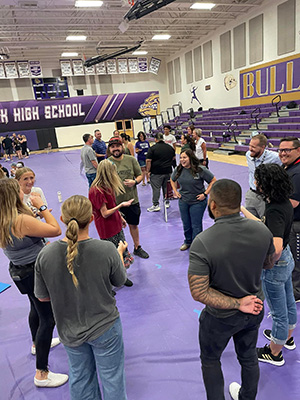 Students and teachers holding their hands out while forming a circle around a female student