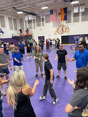 Students and teachers holding their hands out while forming a circle around a female student