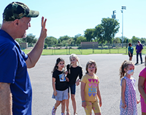 Staff worker waving to students in parking lot