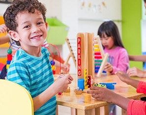 Young boy smiling while working with building blocks